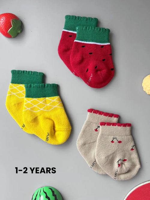Air Garb brand baby combo socks for infants; a 6-pair set of soft cotton socks featuring pineapple, watermelon, cherry, and cute character face designs in vibrant colors like yellow, red, and blue.